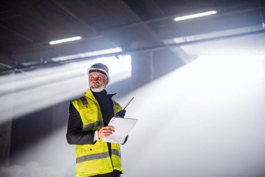 Man engineer using walkie talkie on construction site.