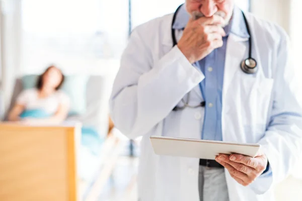 Médico idoso irreconhecível em pé no quarto do hospital, usando tablet . — Fotografia de Stock