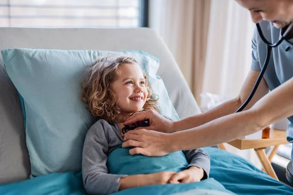 Friendly female doctor examining small girl in bed in hospital. — Stock Photo, Image