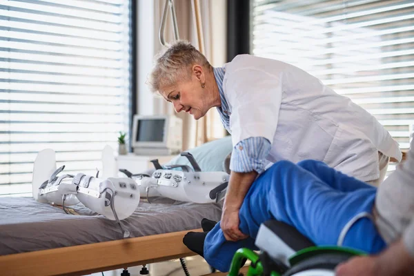 Un operatore sanitario e un paziente anziano paralizzato in ospedale . — Foto Stock