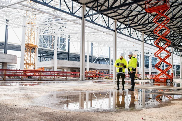 Mannen ingenieurs staan buiten op de bouwplaats, met behulp van tablet. — Stockfoto