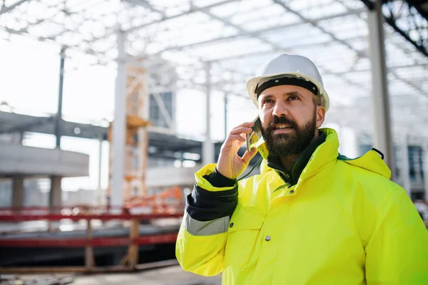 Man engineer staat op bouwplaats, met behulp van smartphone. — Stockfoto