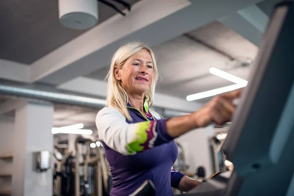 Una mujer mayor en el gimnasio haciendo ejercicio cardiovascular . —  Fotos de Stock