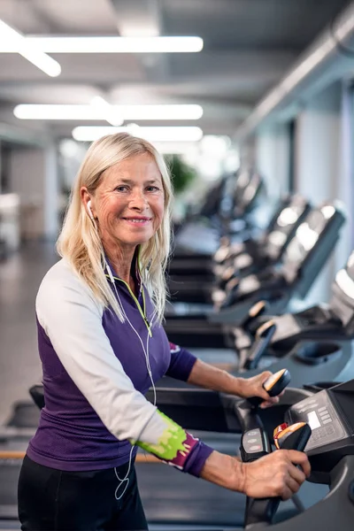 Uma mulher idosa no ginásio fazendo exercício cardiológico . — Fotografia de Stock