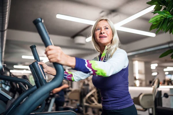 Una mujer mayor en el gimnasio haciendo ejercicio cardiovascular . —  Fotos de Stock