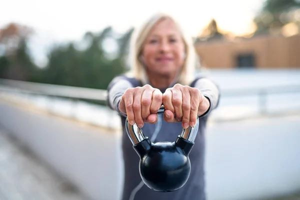 Eine Seniorin mit Kettlebell beim Sport im Freien. — Stockfoto