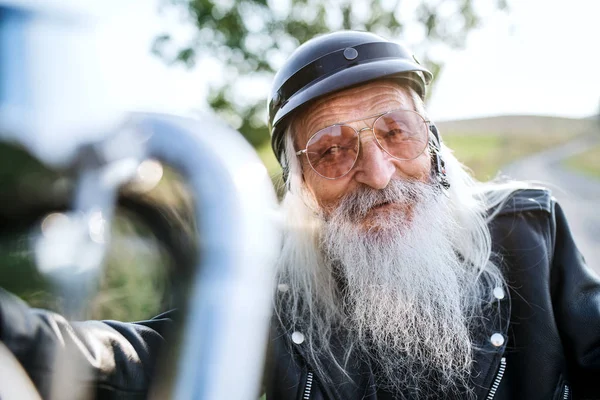 Een seniorenreiziger met motor op het platteland. — Stockfoto