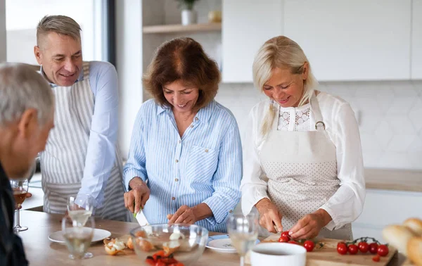 Група старших друзів на вечірці вдома, приготування їжі . — стокове фото