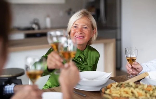 Gruppe älterer Freunde bei Dinnerparty zu Hause, Gläser klirren. — Stockfoto