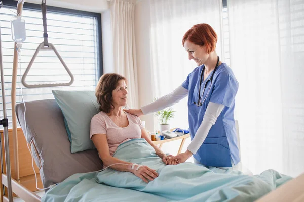 Médecin femme examinant la patiente au lit à l'hôpital . — Photo