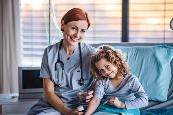 Friendly female doctor examining small girl in bed in hospital. — Stock Photo, Image