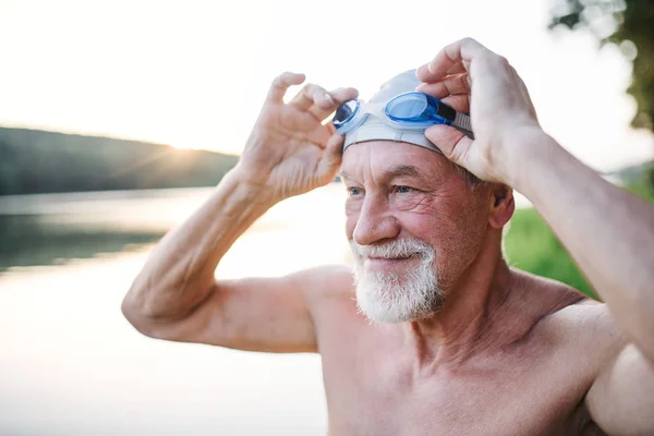 Homem sênior de maiô em pé junto ao lago ao ar livre antes de nadar . — Fotografia de Stock