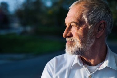 Senior man standing outside in spring nature. Copy space.