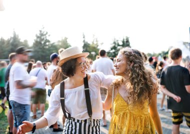 Two young women friends walking at summer festival.
