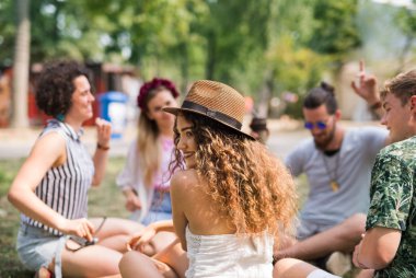 Yaz festivalinde bir grup genç arkadaş yerde oturuyor..