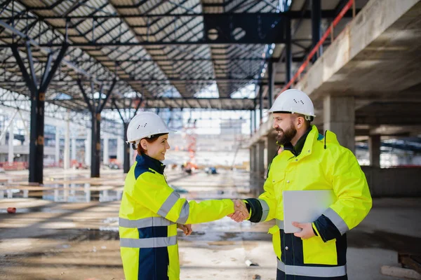 Engineers with tablet standing on construction site, shaking hands. — 스톡 사진