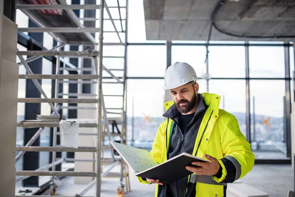 Man engineer standing on construction site, holding blueprints. — 스톡 사진