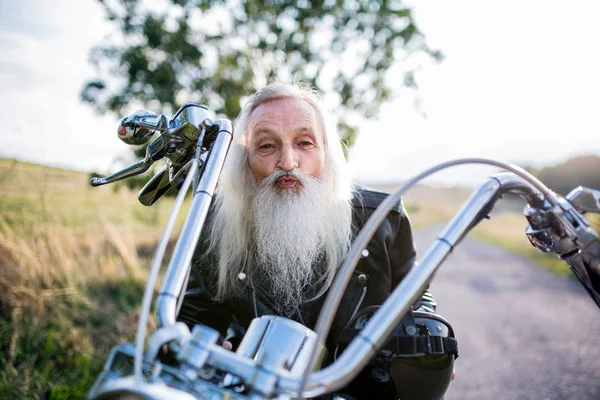 Senior man traveller with motorbike in countryside, having fun. — Stock Photo, Image