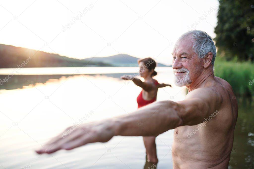 Senior couple in swimsuit standing in lake outdoors before swimming.
