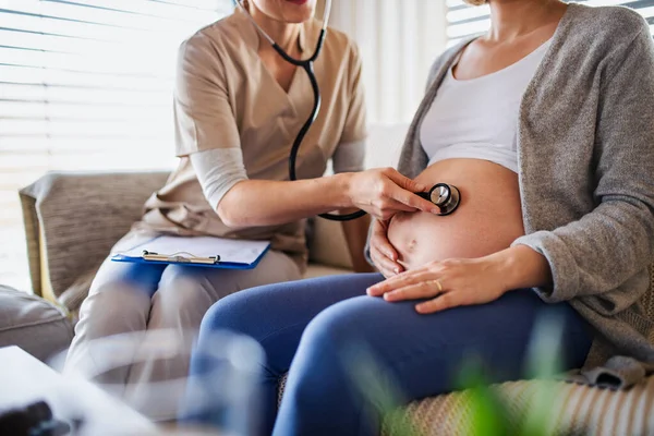 Een middendeel van een gezondheidswerker die een zwangere vrouw thuis onderzoekt. — Stockfoto