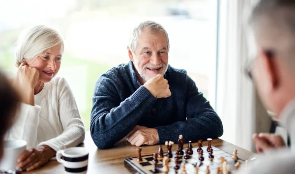 Amigos de xadrez e jogos de tabuleiro na mesa de madeira pensando em  movimento estratégico ou tático em casa grupo sênior de homens jogando e  segurando ou movendo a peça branca para