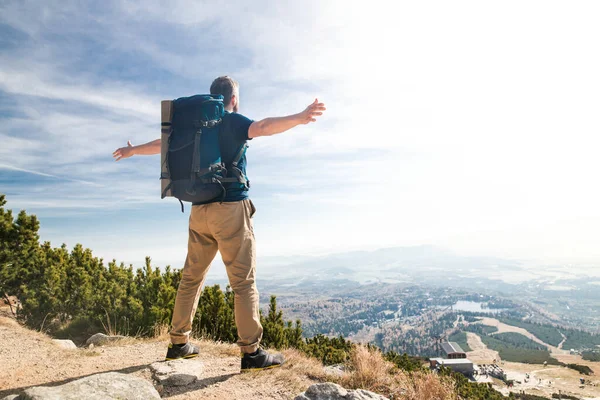 Rear view of man with backpack hiking in mountains in summer. — Stockfoto