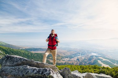 Mature man with backpack hiking in mountains in summer.