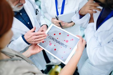 Corona virüsünden bahseden bir grup doktor konferansta, orta kısımda.