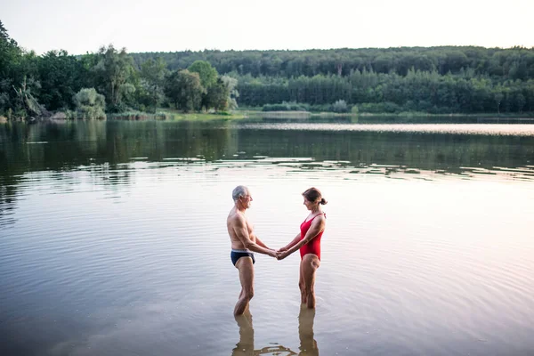 水泳の前に屋外の湖に立つ水着のシニアカップル. — ストック写真