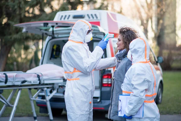 Folk med vernedrakter hjelper kvinner utendørs, konsept med kronavirus . – stockfoto