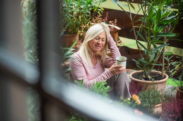 Mujer mayor con café sentado al aire libre en la terraza, descansando . — Foto de Stock