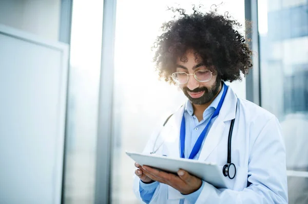 Porträtt av manlig läkare stående på sjukhus, med hjälp av tablett. — Stockfoto