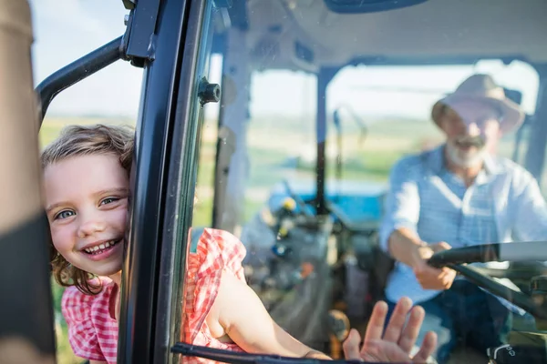 Granjero mayor con nieta pequeña sentada en tractor, conduciendo . — Foto de Stock