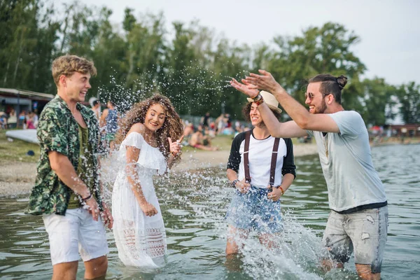 Grupo de jóvenes amigos en el festival de verano, de pie en el lago . —  Fotos de Stock