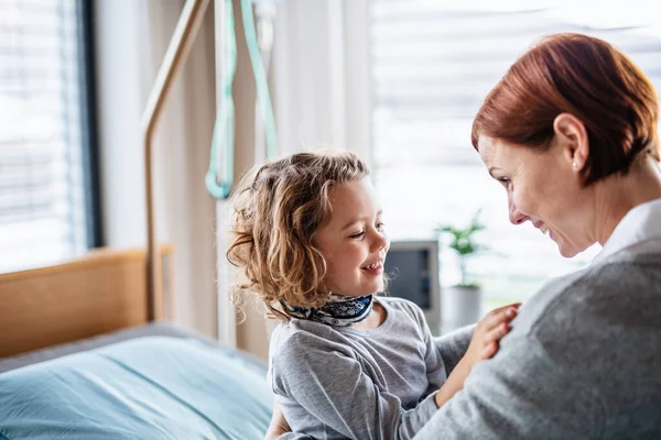 Caring mother visiting small girl daughter in bed in hospital. — Stock Photo, Image