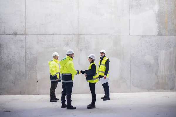 Gruppo di ingegneri in piedi sul cantiere, stringendo la mano . — Foto Stock