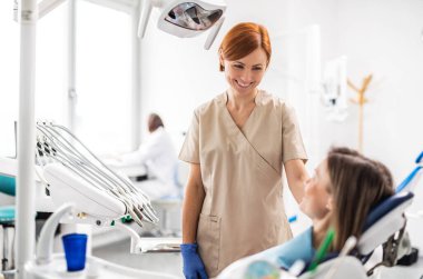 A dentist talking to woman in dental surgery, annual check-up.