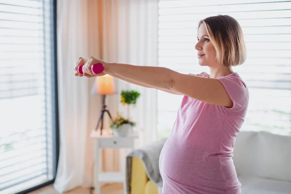 Retrato de mulher grávida dentro de casa, fazendo exercício . — Fotografia de Stock