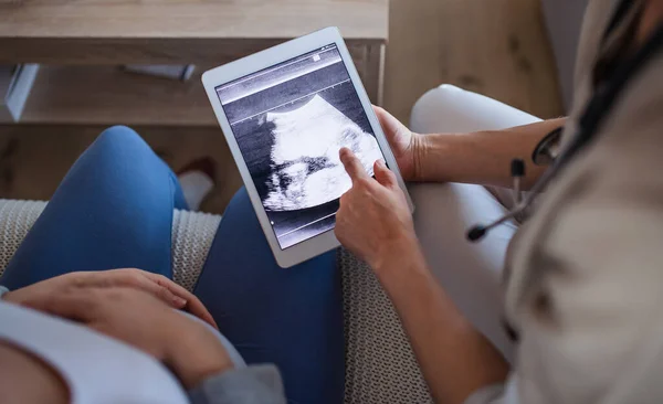 Unrecognizable healthcare worker with ultrasound on tablet and pregnant woman. — Stockfoto