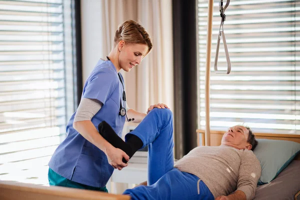 Sjukvårdspersonal och seniorpatient på sjukhus, sjukgymnastik. — Stockfoto