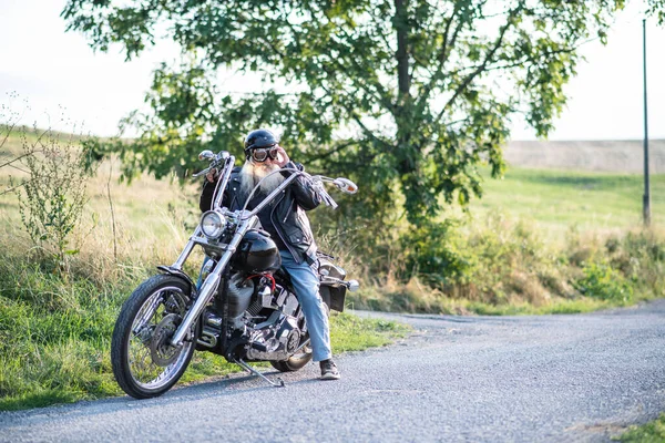 Starszy mężczyzna podróżnik z motocyklem i goglami na wsi. — Zdjęcie stockowe