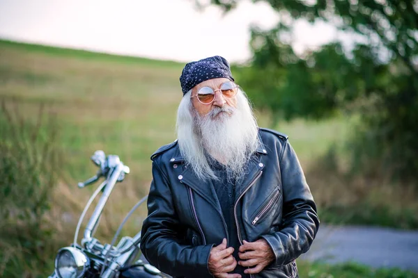 Hombre mayor viajero con moto y gafas de sol en el campo . — Foto de Stock