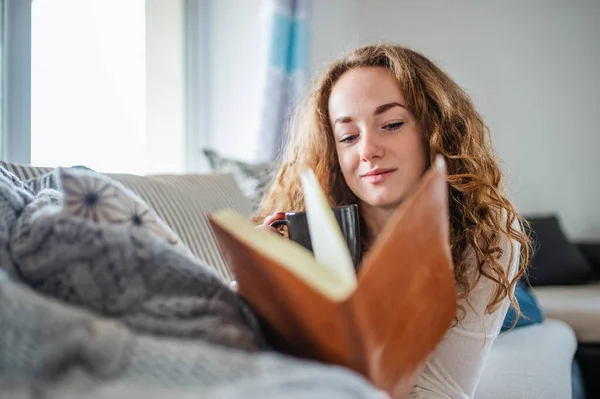 Young woman relaxing indoors at home with book. — Stockfoto
