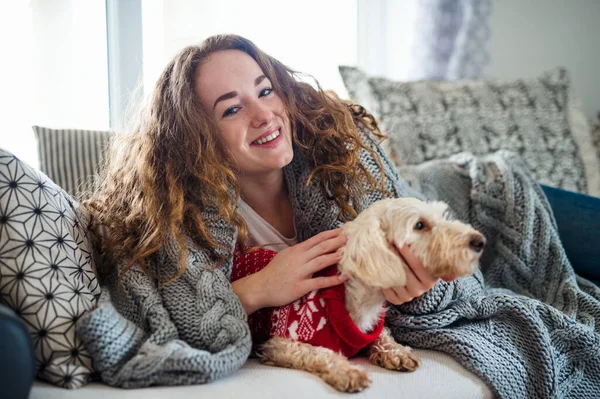 Mujer joven relajándose en el interior en el sofá en casa con perro de compañía . —  Fotos de Stock