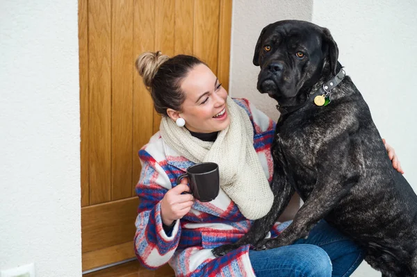 Mujer joven relajándose al aire libre por la puerta principal en casa con perro mascota . —  Fotos de Stock