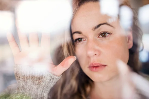 Young sad and depressed woman indoors by window at home. — Stock Photo, Image