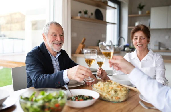 Gruppo di amici anziani a cena a casa, bicchieri di clinking . — Foto Stock