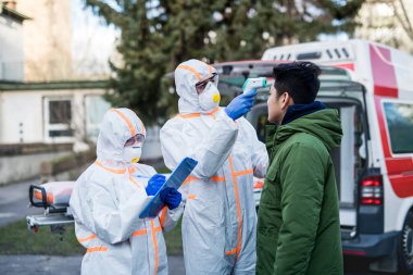Koruyucu elbiseli insanlar insanlara dışarıda yardım ediyor, koronavirüs konsepti..
