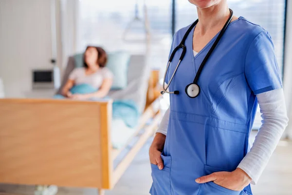 Médecin méconnaissable debout dans la chambre d'hôpital, patient en arrière-plan . — Photo