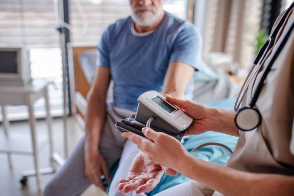 Médecin féminin méconnaissable examinant une patiente âgée au lit à l'hôpital . — Photo